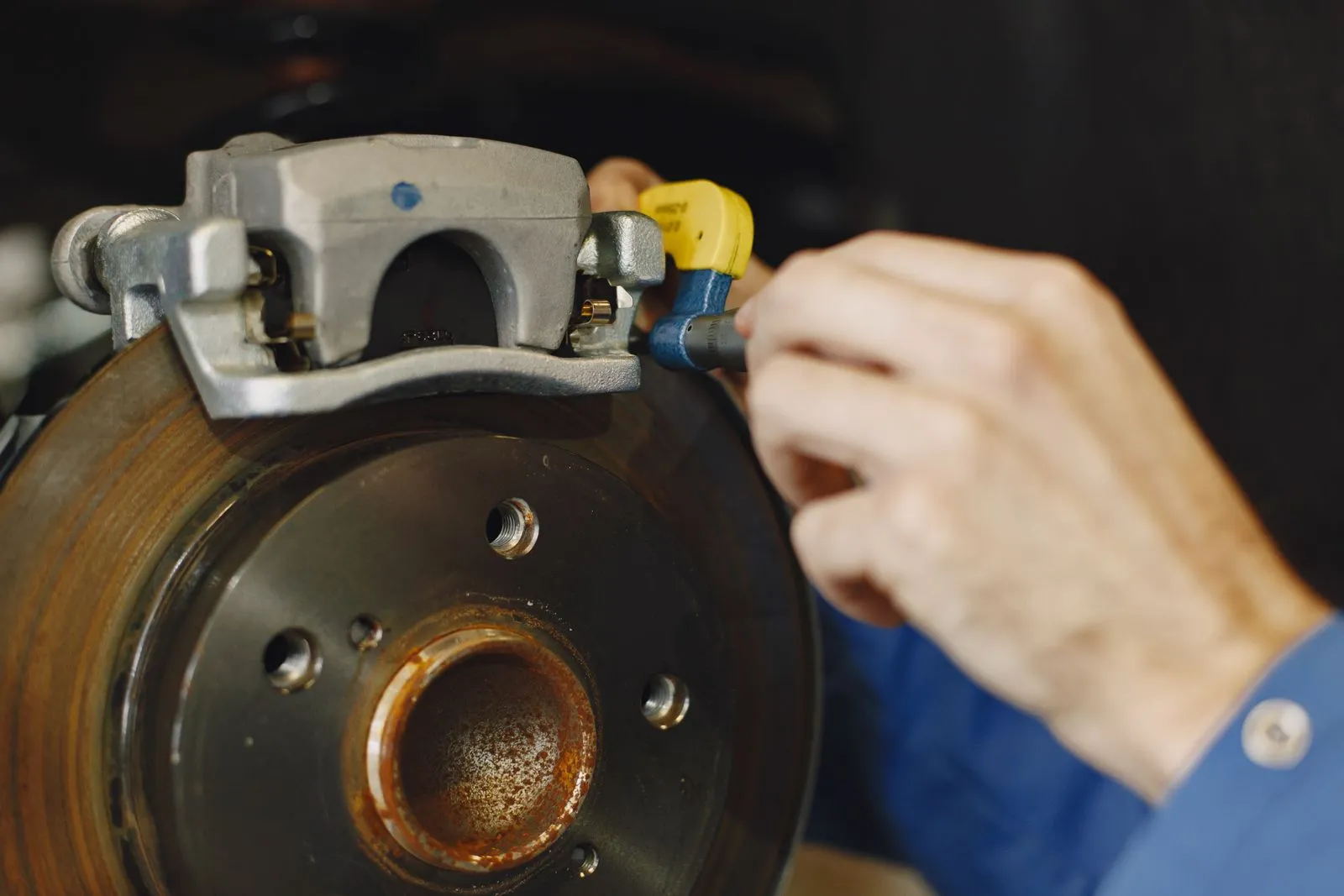 ブレーキのディスクとキャリパーを点検する整備士の手元。ドバイの車検にあたる RTA テストでも足回りが見られる