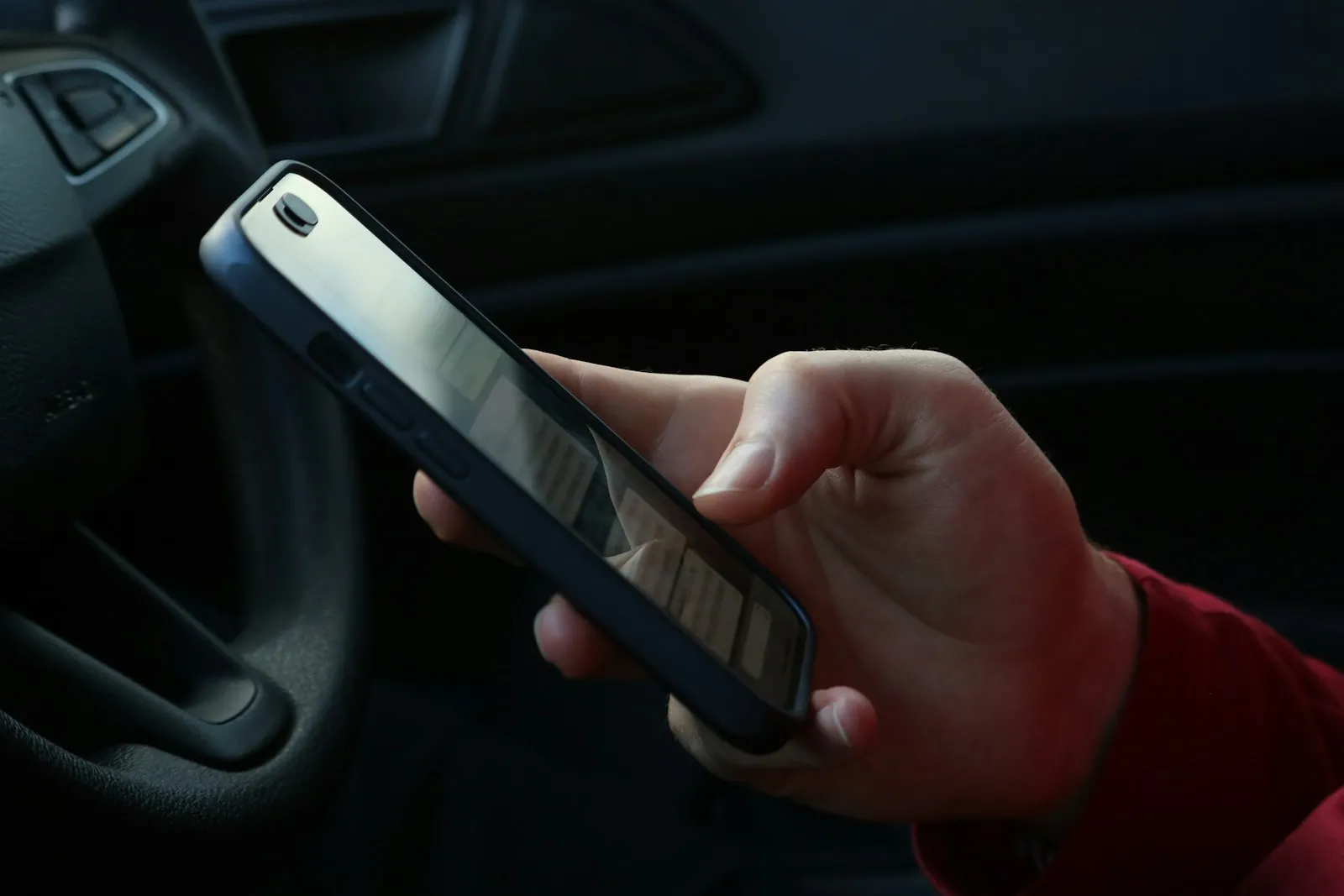 停めた車の運転席でスマートフォンを操作する手元。ドバイの Mulkia 更新は RTA のアプリから手続きできる
